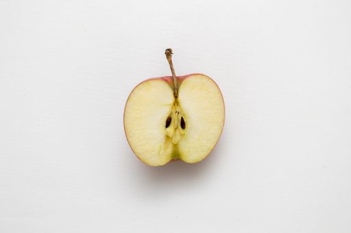 A closeup shot of a  red apple cut in half on a white background