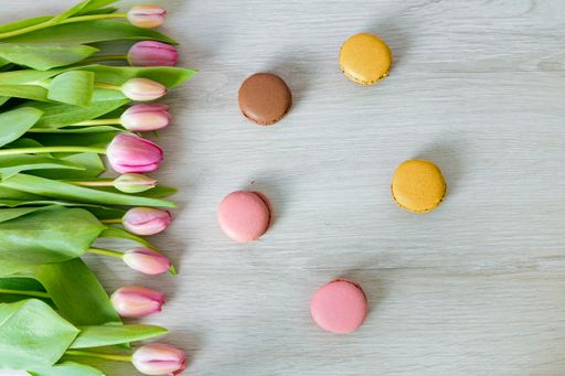 The pink tulip flowers and macaroons over the white wooden table
