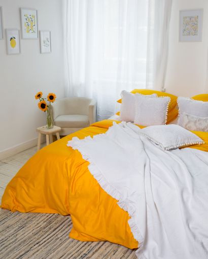 A vertical shot of a cozy bedroom with a white blanket and pillows