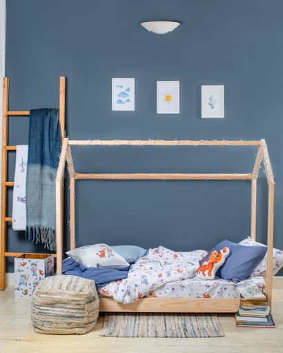 A vertical shot of a cozy bedroom with blue pillows and  pictures