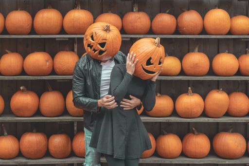 A view of couple wearing pumpkins on head