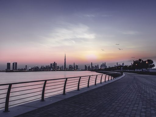A beautiful shot of a walking area beside the river and the colorful sunset sky in the background