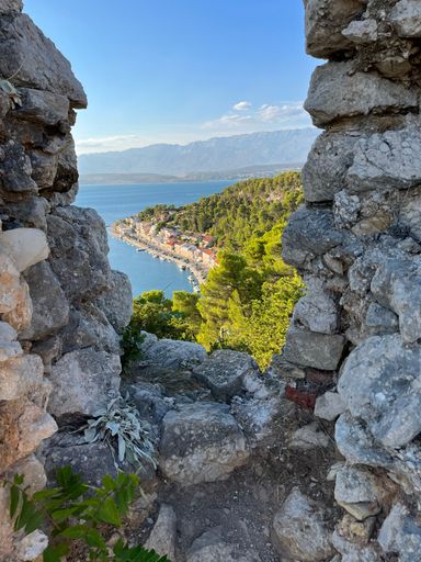 A vertical shot of a coastal town and green nature view from an old stone fortress
