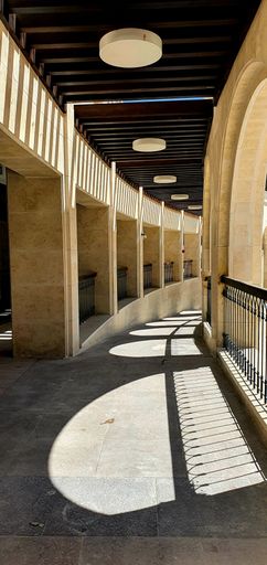 A vertical shot from the inside of a modern building's balcony, with sunlight coming through