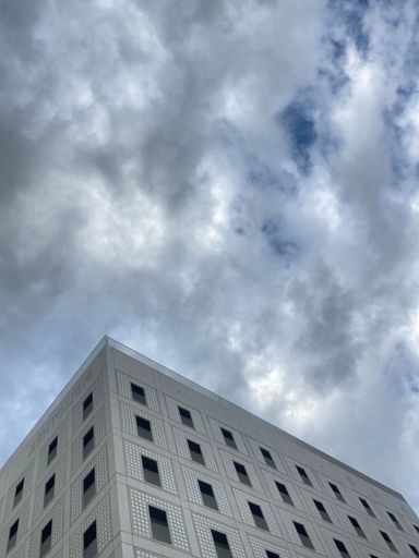 A vertical low-angle shot of a modern building against the background of the cloudy sky.