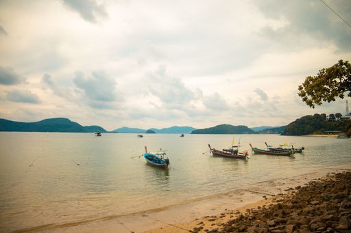 A beautiful shot of small boats in the sea next to the shore on a cloudy day