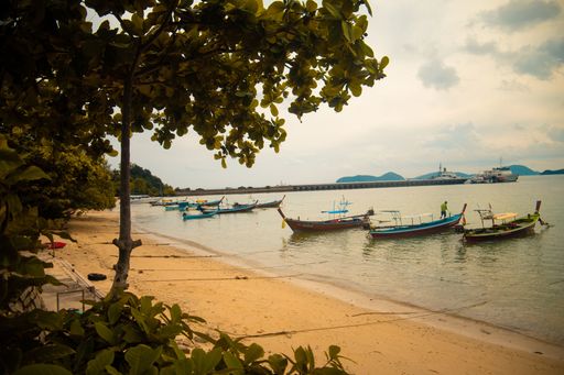 A beautiful shot of small boats in the sea next to the shore on a cloudy day