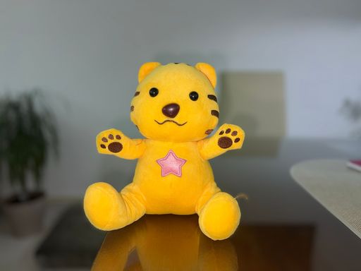 A cute yellow bear plush toy, stuffed animal isolated on a blurred background