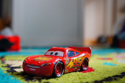 Disney Pixar Lighting McQueen toy model car on a carpet.