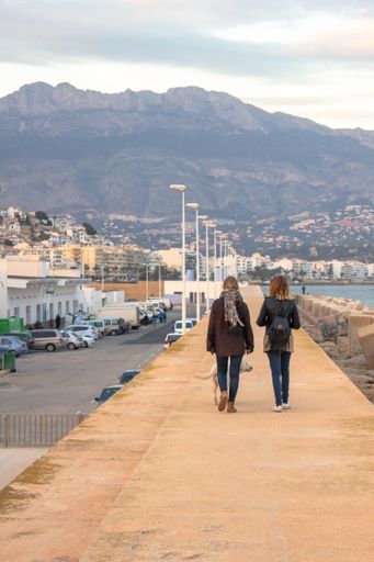 A vertical shot of two young females walking along the beach