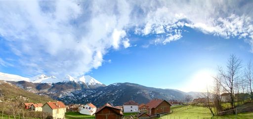 A group of small houses in the rural area with snow-covered mountains in the background