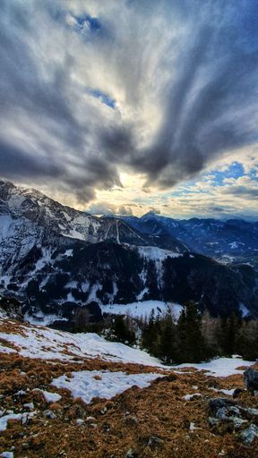 A view of mountains covered by snow under cloudy sky, vertical shot