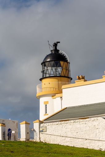 A vertical shot of the Stoer Lighthouse in Scotland against the cloudy sky