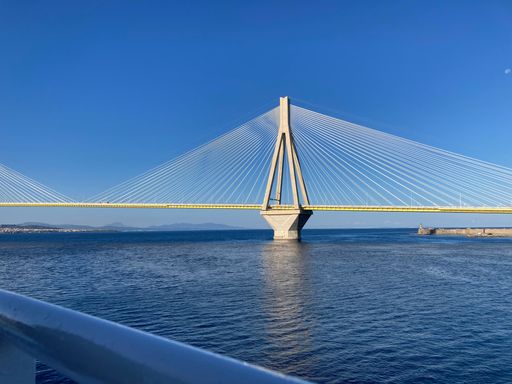 A landscape view of the Rion-Antirion Bridge on blue sea with blue sky background