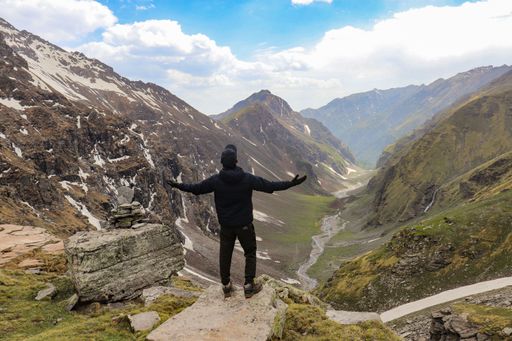 A man standing against a beautiful view in mountains and enjoying it with open arms