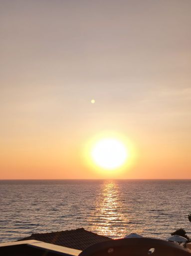A vertical shot of a sea with a sunset sky in the background