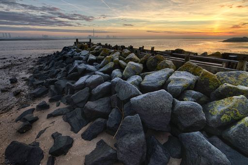 A beautiful sunset at the beach covered in rocks of different shapes and sizes
