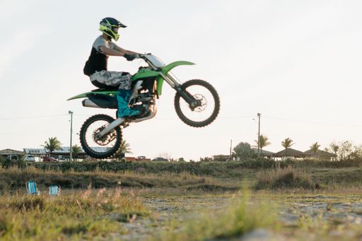 A biker man with a helmet riding a motocross bike and doing the wide-open skill in rural field