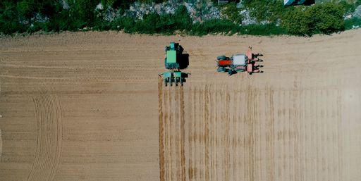 An aerial view of a farmer with machinery seeding and sowing crops at the field