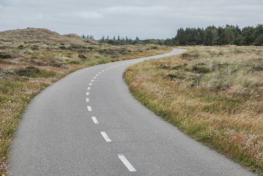A high angle shot of a country road surrounded by fields under the clear sky