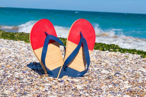 A closeup of colorful flip flops on the beach in sunny weather in daylight