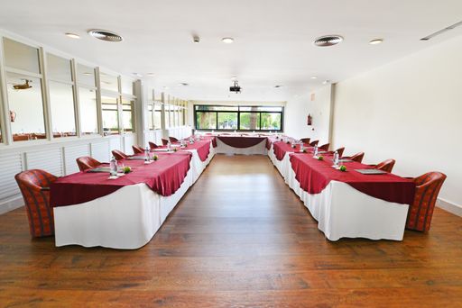 The inside of a conference hall with set-up chairs and tables and a screen on the wall