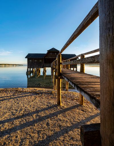 a vertical shot of a wooden boat house at a lake in southern Germany at sunset with blue sky