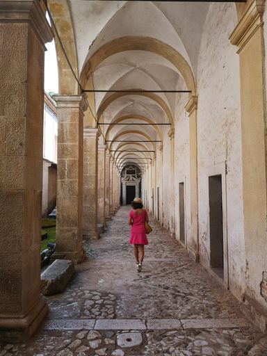 A vertical shot of a woman walking in the hallway of the famous Certosa of Padula in Italy