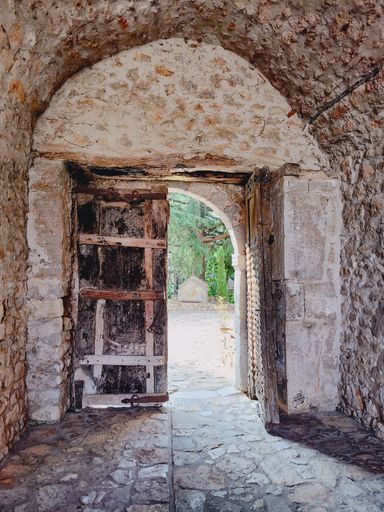A vertical closeup shot of an old stone medieval house with arched entrance and wooden door