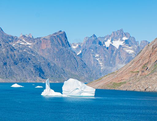 An aerial view of iceberg surrounded by rocky mountains in Prince Christian Sound
