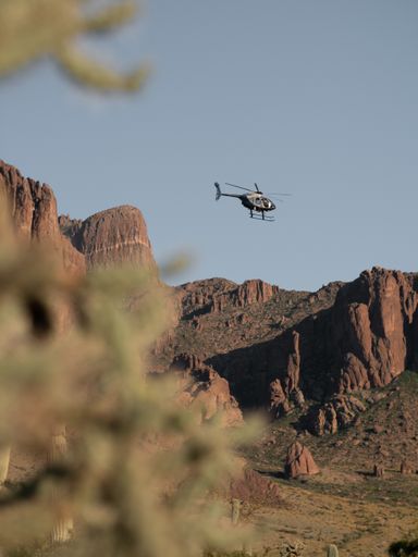A vertical shot of a helicopter flying over a canyon landscape