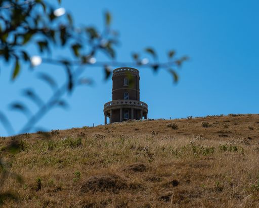 A beautiful view of the Clavell Tower in Kimmeridge, England with hills around it under a bright sky