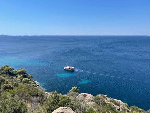 An aerial view of a boat sailing in the vast blue ocean in blue sky background on a sunny day