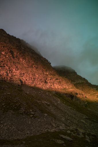 A vertical shot of mountains and fog during the sunset