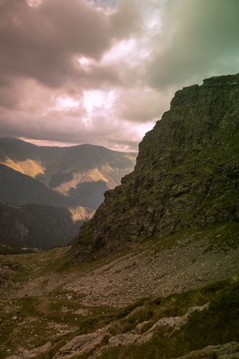 A vertical shot of mountains and fog during the sunset