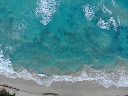 An aerial shot of the beautiful wavy ocean hitting the sandy beach - great for wallpapers