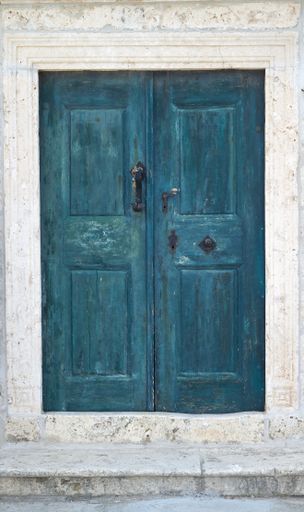 A beautiful closeup of a blue old door on a white building