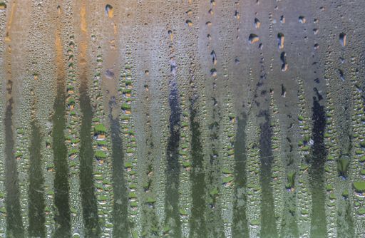Close-up view of the steamed window with the blurred colored background and striped pattern of dew drops