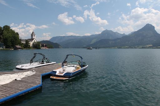 A wooden pier, two boats on a lake near the mountains