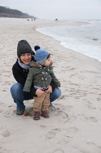Woman and boy close by the water at a sandy beach on a cloudy day