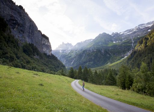 A high angle shot of a male skating on the road in the mountains on a cold day