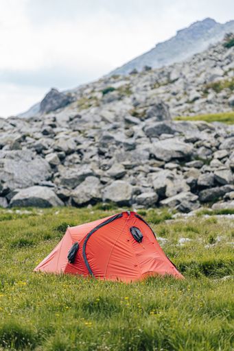 A vertical low angle shot of a red hiking tent in the mountains - perfect for an article about hiking