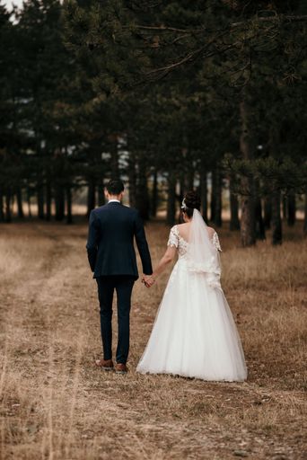 A vertical shot of a married couple holding the hands and walking in the park
