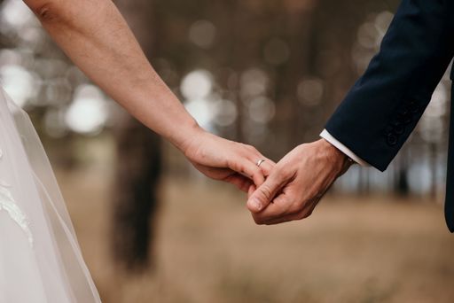 A couple holding each others' hands during the wedding ceremony suit