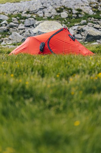 A vertical low angle shot of a red hiking tent in the mountains - perfect for an article about hiking