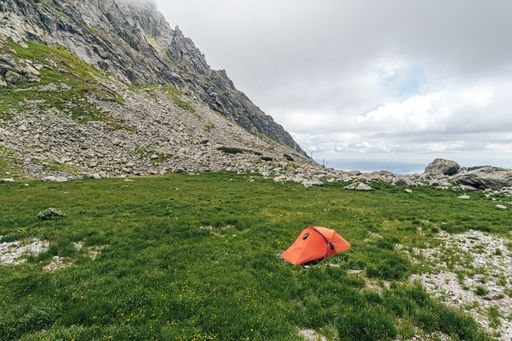 A closeup shot of a red hiking tent in the mountains - perfect for an article about hiking