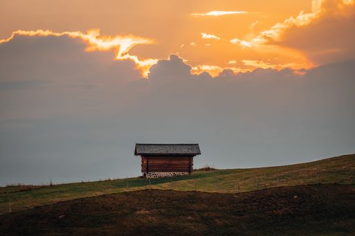 A small wooden hut surrounded by the beautiful Dolomites mountains during the sunset