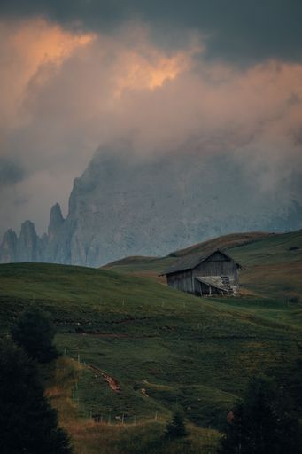 A small wooden hut surrounded by the beautiful Dolomites mountains during the sunset