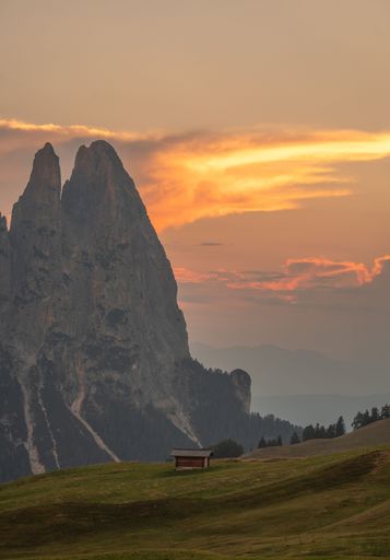 A small wooden hut surrounded by the beautiful Dolomites mountains during the sunset