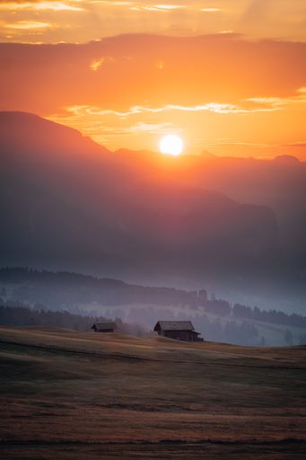 Small wooden huts surrounded by the beautiful Dolomites mountains during the sunset